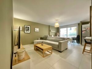 Salon spacieux et lumineux dans un appartement à Sainte-Maxime, avec canapé confortable, décoration contemporaine et grandes fenêtres.
