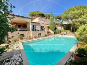 Vue sur une maison provençale depuis la piscine, avec jardin et terrasse.