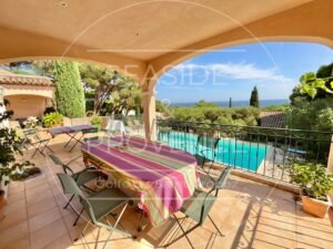 Terrasse couverte avec coin barbecue, vue sur la mer et piscine, espace idéal pour repas en famille.