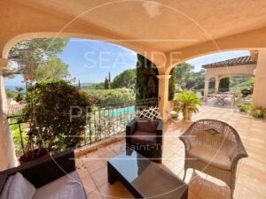 Coin détente sur une grande terrasse avec vue mer en arrière-plan, espace ombragé pour lire ou discuter.