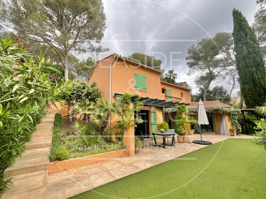 Vue extérieure de la villa à vendre à Fréjus depuis le jardin, façade claire et espace vert arboré.