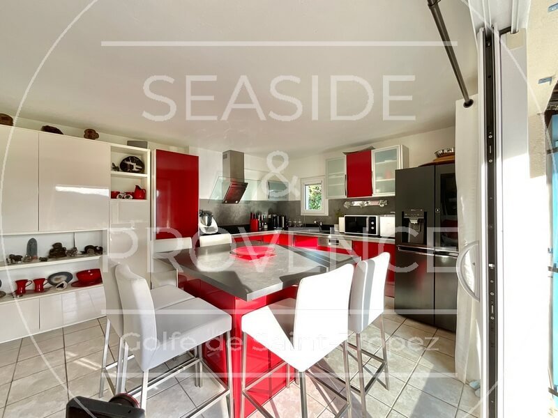 Cuisine ouverte sur le salon avec porte-fenêtre vers la terrasse, située en partie basse au Plan-de-la-Tour