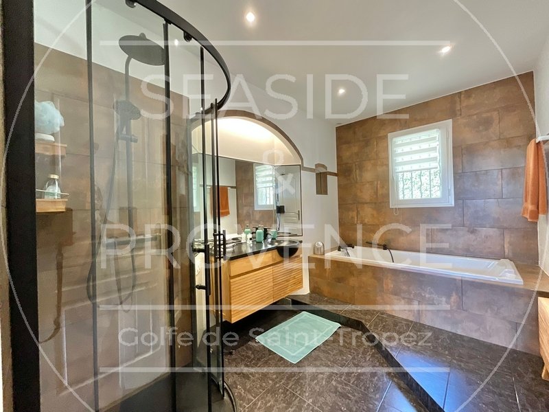 Salle de bains avec baignoire, douche vitrée et meuble vasque en bois